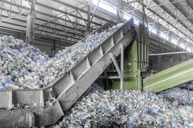 Escalera mecánica con un montón de botellas de plástico en la fábrica para su procesamiento y reciclaje