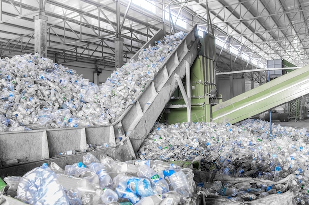 Escalera mecánica con un montón de botellas de plástico en la fábrica para su procesamiento y reciclaje