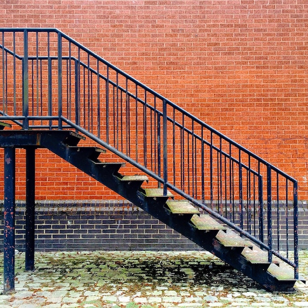 Foto escalera de metal contra la pared de ladrillo