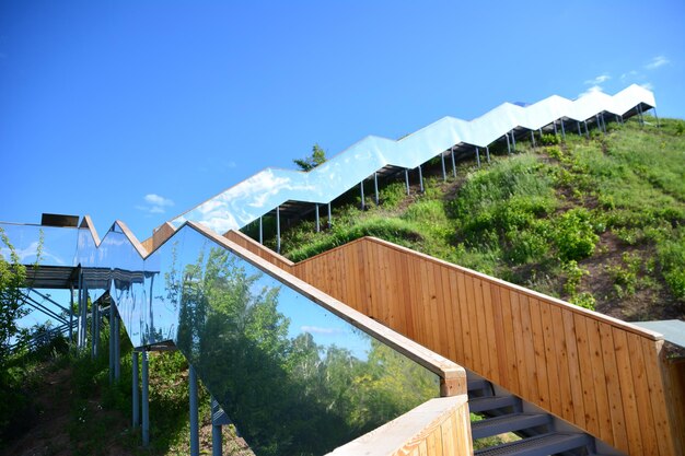 escalera con pared de espejo subiendo con cielo azul en el fondo espacio de copia