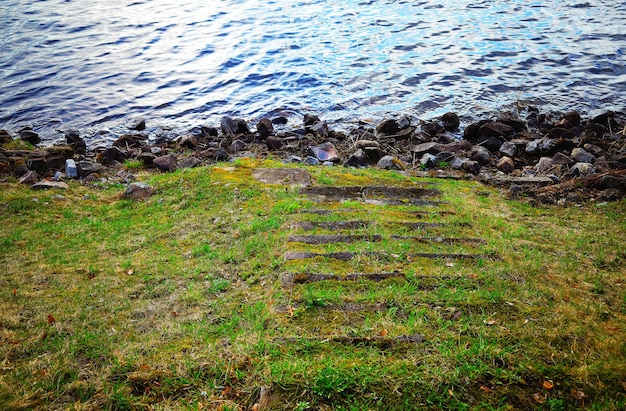 Escaleras cubiertas de hierba hacia el paisaje rocoso de la orilla del río