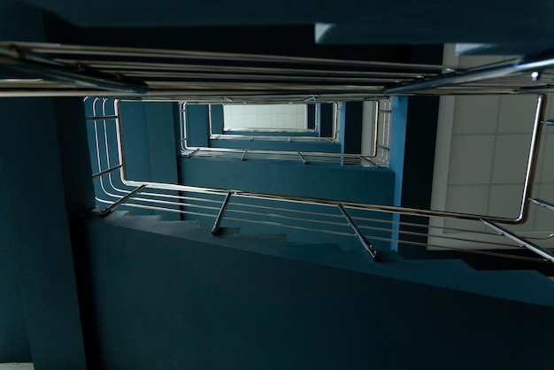 Escaleras en un edificio de oficinas de hormigón en tonos neutros cubiertas de baldosas de cerámica con barandillas de metal brillante