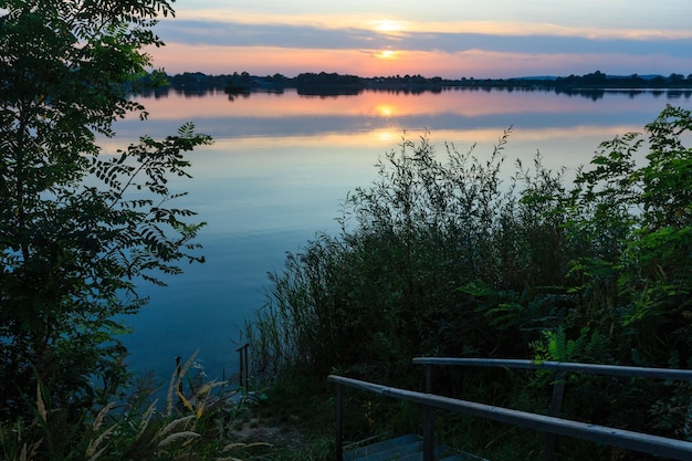 Escaleras de madera al lago del atardecer de verano