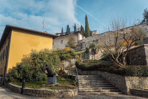 Escaleras pavimentadas con piedra. Castello di Brescia, Lombardía, Italia. Parte del castillo de la ciudad de Brescia en un soleado día de invierno. Castillo medieval con almenas, torre, puente levadizo y murallas.