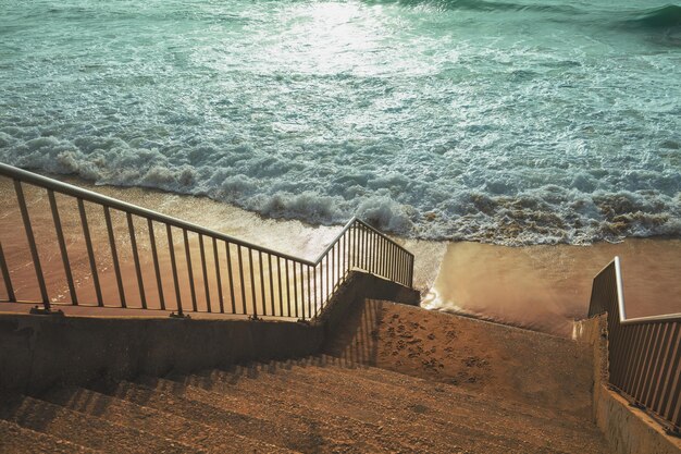 Escaleras a la playa de arena durante una tormenta al atardecer