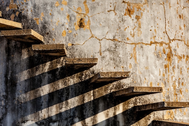Escaleras proyectando sombra sobre la antigua muralla desgastada