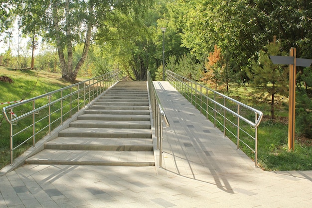 Escaleras y rampa con barandillas metálicas para el paso de cochecitos y sillas de ruedas en parque público. Estafa