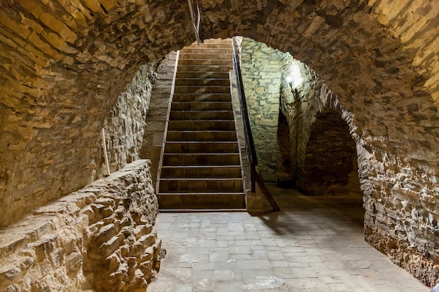 Escaleras viejas abandonadas con paredes agrietadas a un sótano de una antigua fortaleza.