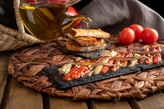 Foto escalivada regada con aceite de oliva virgen y verduras en una cesta de mimbre sobre la rústica mesa de madera.