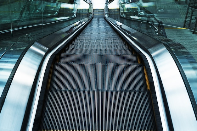 Los escalones de la escalera mecánica descienden en las salas de espera de la estación. Subiendo las escaleras. escalera mecánica eléctrica. Enfoque selectivo