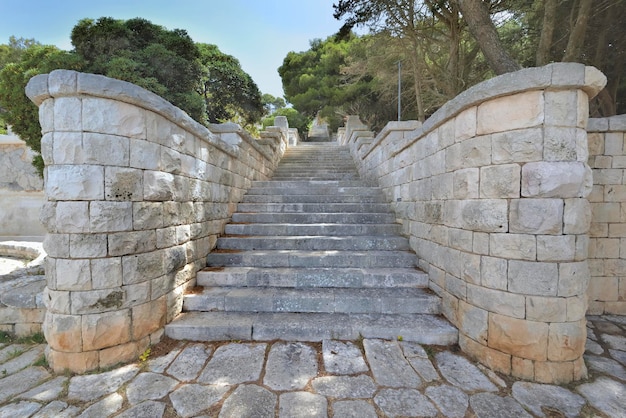 Escalones de piedra de un straicase al aire libre subiendo muy alto en un parque de Puglia en Italia