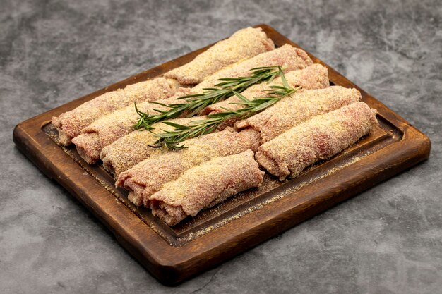 Escalope de ternera sobre fondo oscuro Delicioso escalope de carne cruda preparado con pan rallado y sésamo blanco