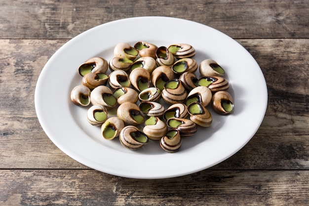 Escargots de Bourgogne en mesa de madera.