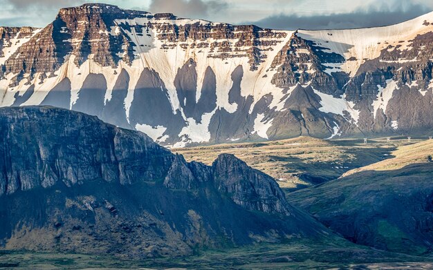 Foto la escarpada cordillera domina el espectacular paisaje durante un breve verano islandés