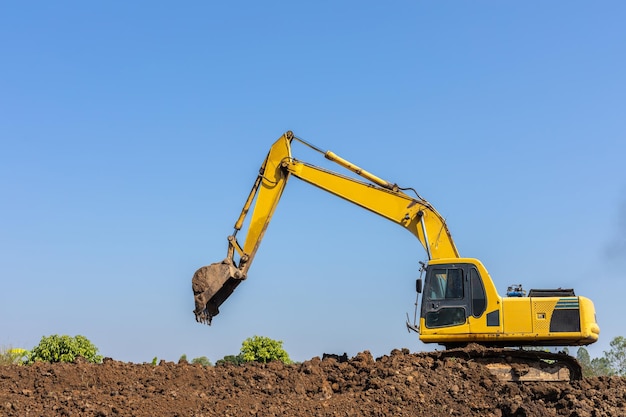Escavadeira amarela escavando a máquina escavadora ajustando o nível do solo no canteiro de obras