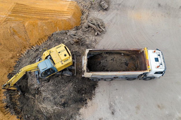 Escavadeira carrega areia em uma vista superior de caminhão