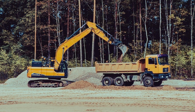 Escavadeira de esteira laranja e caminhão basculante de construção Carregando areia