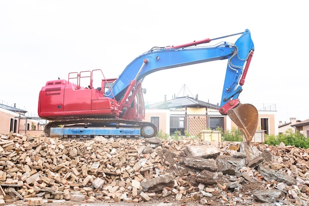 Escavadeira de esteiras sobre os escombros de um edifício na área residencial máquina escavadora de esteiras com caçamba para remoção do local para limpar a área para novas construções conceito de reconstrução de demolição