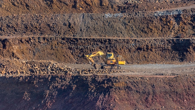 Foto escavadeira hidráulica amarela com rodas de esteiras na mina com fundo marrom