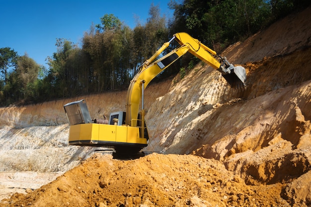 Escavadeira industrial trabalhando no canteiro de obras para limpar a terra de areia e solo