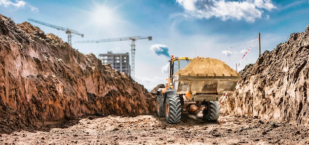 Escavadeira ou carregador trabalhando na trincheira Poderosa carregadeira ou escavadeira com uma caçamba grande em um canteiro de obras Aluguel de equipamentos de construção