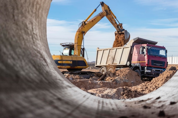 Escavadeira pesada no canteiro de obras Vista da escavadeira através do tubo de ferro Equipamento de construção para terraplanagem Escavadeira de pedreira