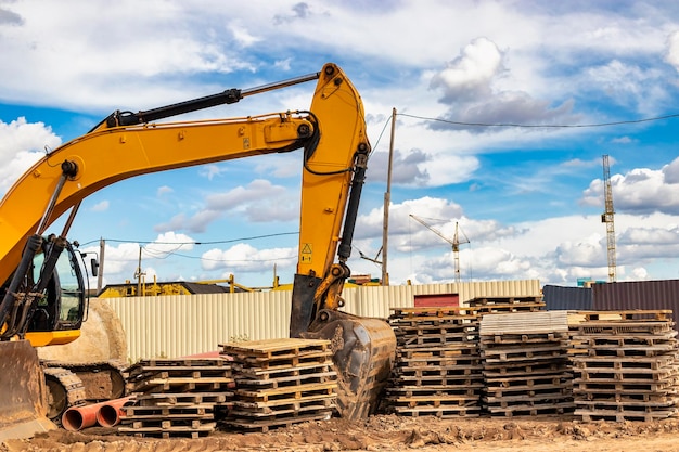 Escavadeira poderosa em um canteiro de obras contra um céu azul nublado Equipamento de movimentação de terra para construção Escavadeira entre paletes de madeira