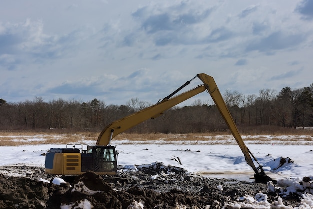 Escavadeiras de movimentação de terra com equipamentos pesados durante a escavação da retroescavadeira do canteiro de obras para a colocação de tubos de esgoto nas obras