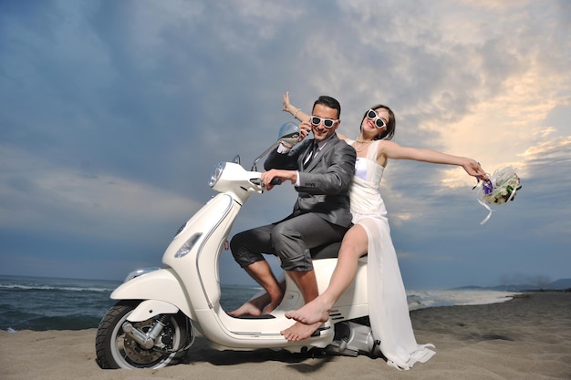 escena de la boda de la novia y el novio pareja de recién casados en la playa andar en scooter blanco y divertirse