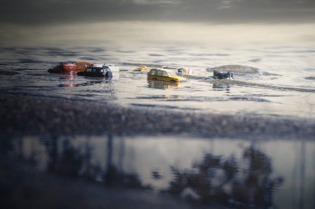 Escena de coches (miniatura, modelo de juguete) en inundaciones por desastres naturales, fuertes lluvias, tifones, huracanes.Transporte, concepto de seguro de automóvil