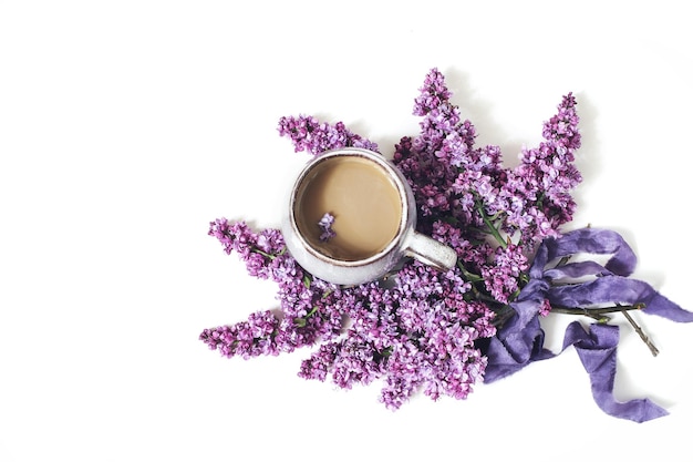 Escena de desayuno de primavera con estilo composición floral femenina Ramo de ramas de lila púrpura cinta de seda y taza de café aislado en el fondo de la mesa blanca Vista superior endecha plana