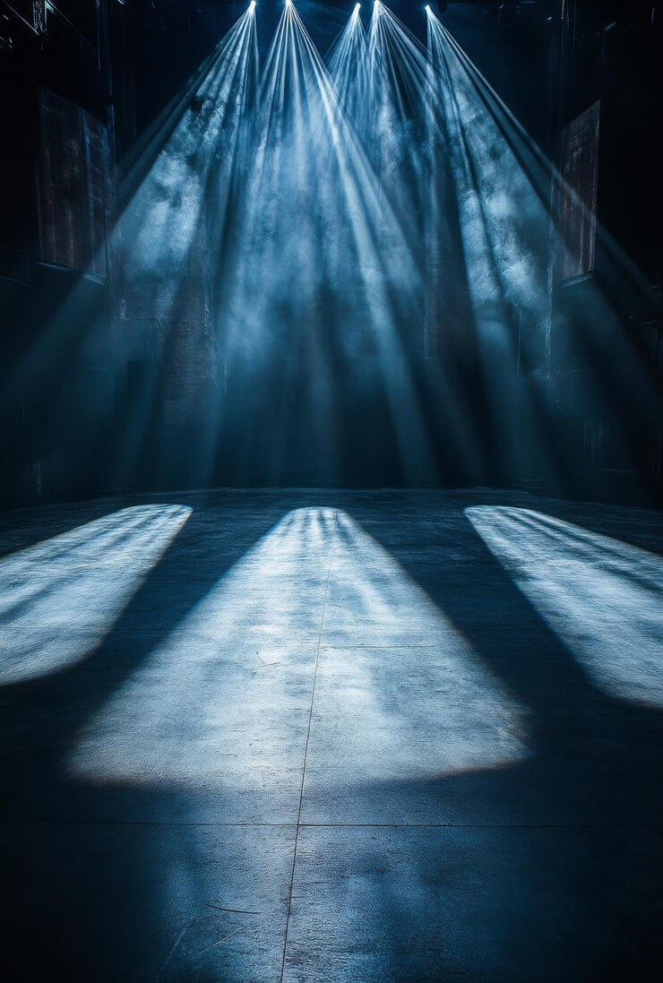Una escena dramática ambientada en un escenario con intensos reflectores que proyectan largas sombras en el suelo evocando una sensación de suspenso y tensión