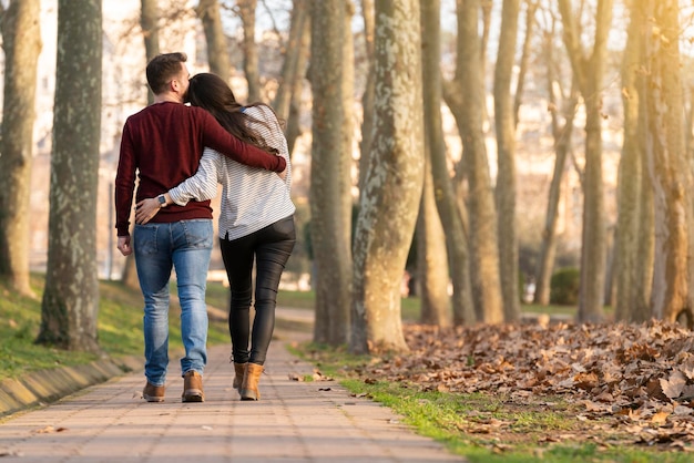 Foto escena feliz y romántica con una joven pareja heterosexual caminando y abrazándose en un parque el día de san valentín
