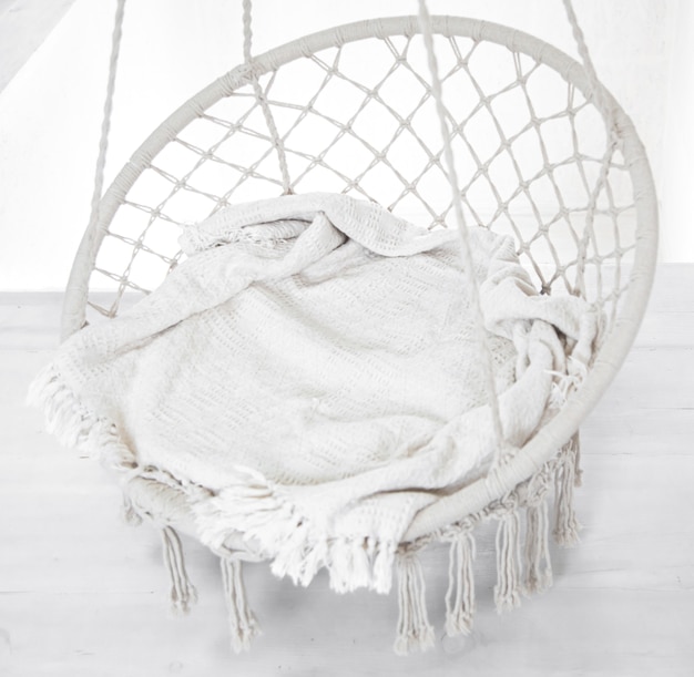 Escena de Hygge con silla hamaca blanca con almohada gris. Lugar acogedor para relajarse en la habitación de fin de semana.