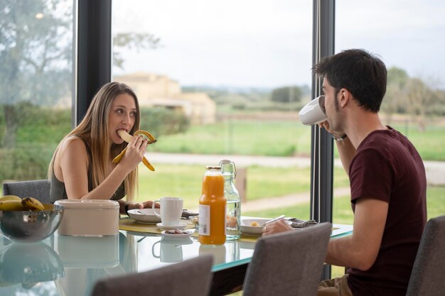 Escena íntima de una pareja joven desayunando en la sala de estar en casa cerca del jardín