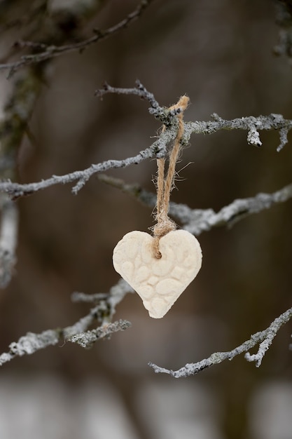Escena de invierno con corazón colgando de un árbol