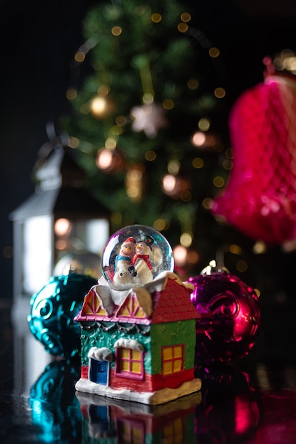 Escena de Navidad con árbol, luces y globo de nieve. Enfoque selectivo