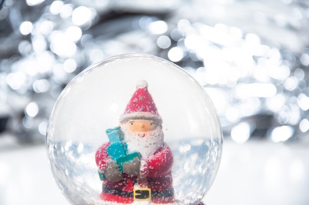 Escena navideña de Papá Noel encantado en una bola de vidrio con copos de nieve que caen