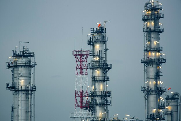 Escena de la noche de la torre de la planta de refinería de petróleo del tanque y la tubería de humo de la destilería de columna