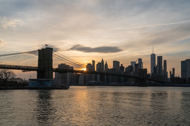 Escena del paisaje urbano de Nueva York con el Puente de Brooklyn sobre el río East en el atardecer, horizonte del centro de Estados Unidos