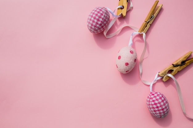 Escena de Pascua con la fila de los huevos y el perno coloreados colgantes aislados en fondo rosado