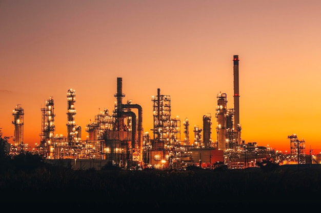 Escena de la planta de refinería de petróleo de petroquímica Refinería de petróleo y planta e industria de humo de combustión en la industria del petróleo y el gas con cielo rojo y naranja de nubes por la mañana