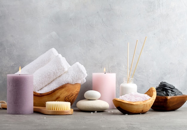 Escena de spa relajante con velas, flores y piedras en una mesa de madera en el centro de bienestar