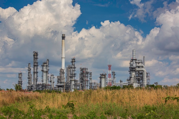 Escena de la tarde de la torre de la planta de refinería de petróleo del tanque y el tanque de columna de aceite de la industria petroquímica cielo azul y césped