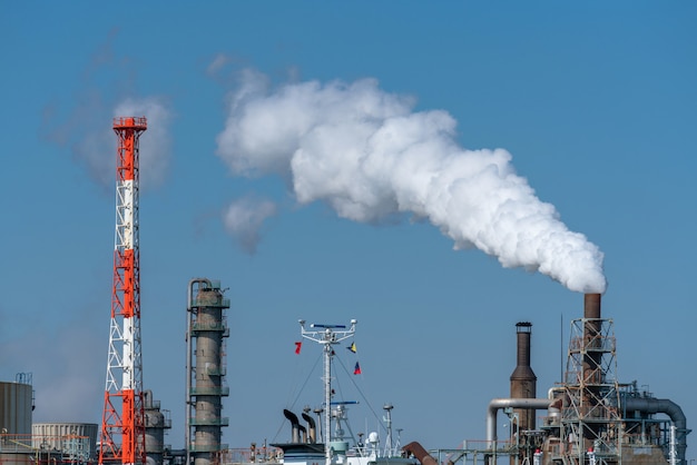 Escena de la zona industrial de la refinería de petróleo junto al río en la hora de trabajo que tiene humo de vapor