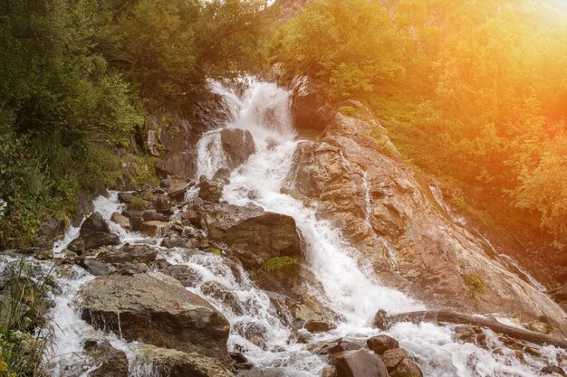 Escenas de la cascada de la visión del primer en las montañas, parque nacional Dombai, Cáucaso, Rusia, Europa. Paisaje de verano, clima soleado y día soleado.