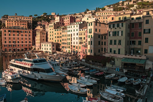 Escénica costa de la riviera mediterránea. Vista del atardecer de la ciudad de Camogli en Liguria, Italia. Fondo de viaje con coloridas casas y barcos.