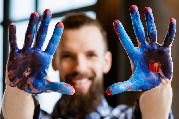 Escola de arte moderna Aula de mestre de pintura Passatempo criativo e lazer Closeup de mãos de homem sujas com tinta acrílica azul e vermelha