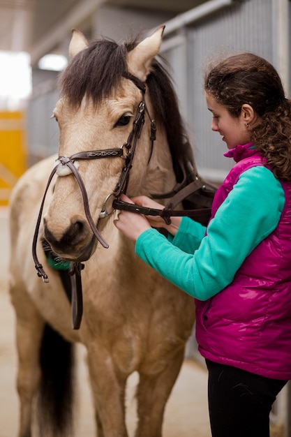 Escola de equitação jovens mulheres hispânicas cuidam e preparam o esporte a cavalo no estábulo