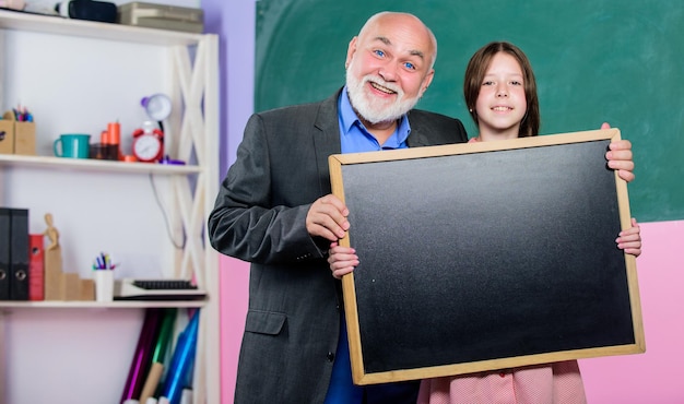 Escola Melhor para um Amanhã Melhor professora madura e aluna feliz sala de aula menina pequena com professor tutor quadro-negro para informações e anúncios Espaço para cópia Vendas escolares